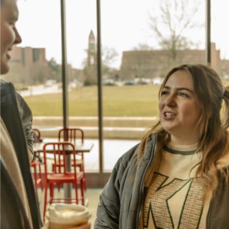 Two Digital Corps students in a dining hall talking together