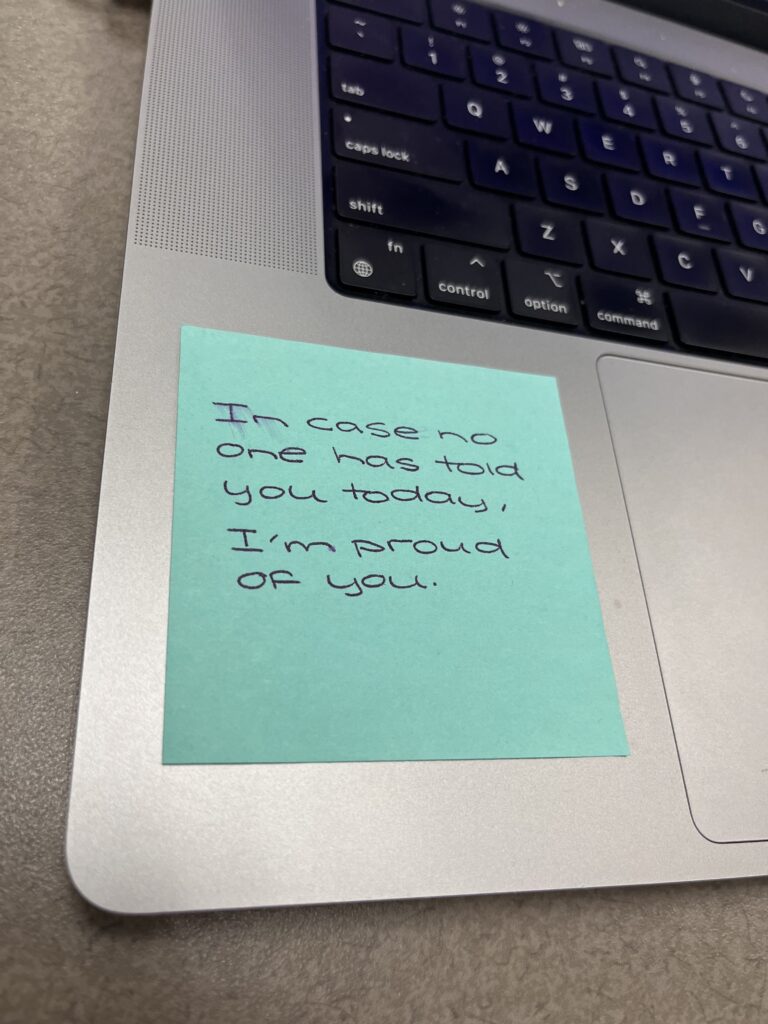A sticky note on the base of a computer reading, "In case no one has told you today, I'm proud of you."